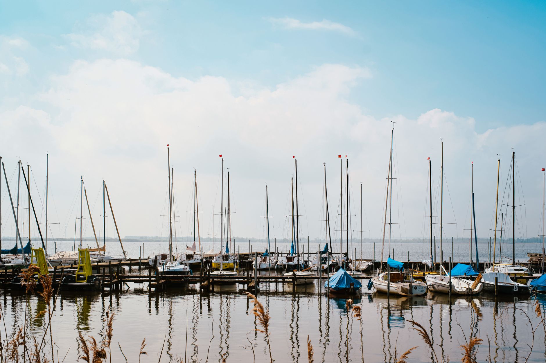Sailboats moored along wooden docks at a calm lake marina