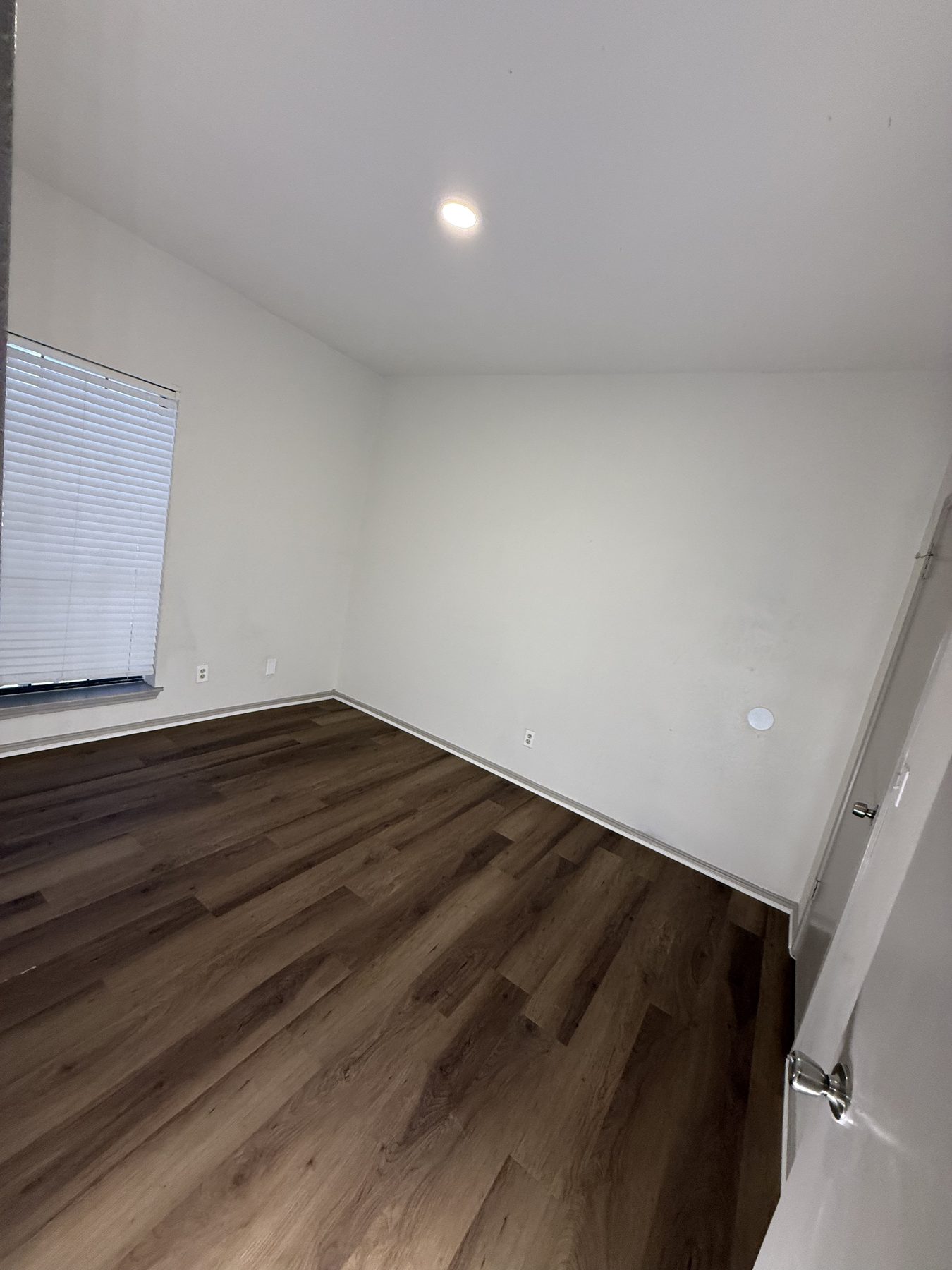 Bright bedroom with wood-look flooring and a large window